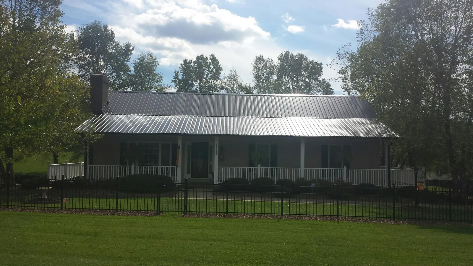 Gray metal roof on a brick ranch with a full width front porch — Gutter Guard Installation work by our crew in Troy
